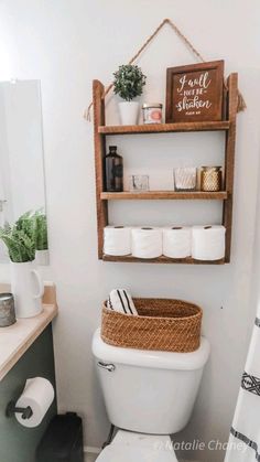 a white toilet sitting in a bathroom next to a wooden shelf