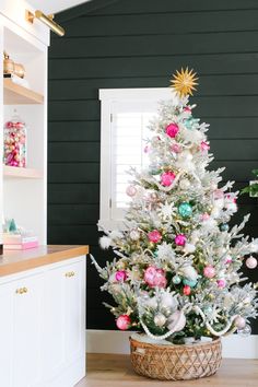 a white christmas tree with pink, green and gold ornaments