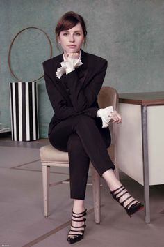 a woman sitting on top of a chair wearing black and white shoes with her legs crossed