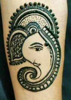 a henna tattoo on the leg of a person with an intricate head and eyes