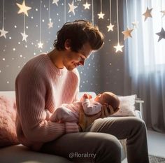 a man holding a baby in his lap while sitting on a couch with stars hanging from the ceiling