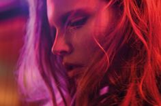 a close up of a woman's face with red hair and bright lights in the background