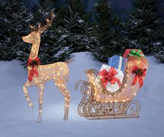 two lighted reindeer sleighs with presents on them in the snow at night