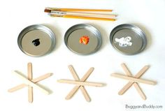 four tins with paint and wooden sticks sticking out of them next to an apple