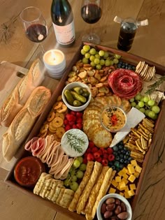 a wine bottle and some snacks in a tray on a table next to two glasses