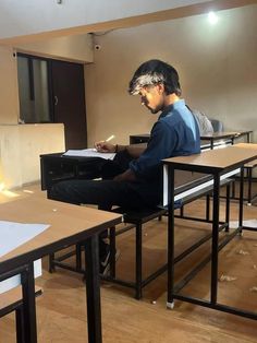 a man sitting at a desk writing on a piece of paper