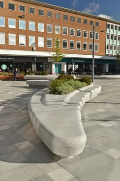 a bench sitting in the middle of a courtyard next to a tall building with lots of windows