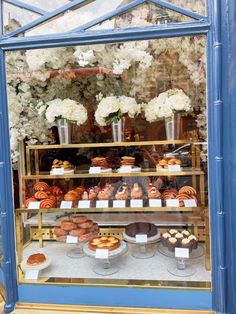 a display case filled with lots of different types of pastries in front of a window