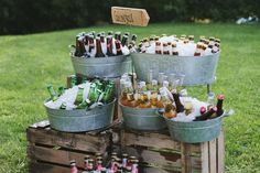 several buckets filled with beer sitting on top of a grass covered field next to trees