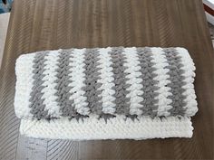 a gray and white blanket sitting on top of a wooden table