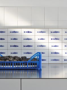 a blue and white fish tile backsplash with rocks in the bottom right hand corner