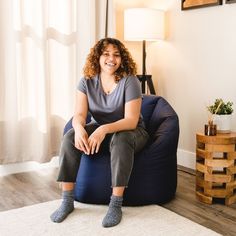 a woman is sitting on a bean bag chair in the living room with her legs crossed