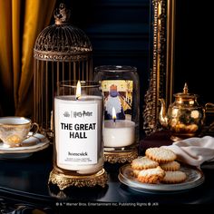 a candle and cookies on a table with a birdcage in the background that says the great hall