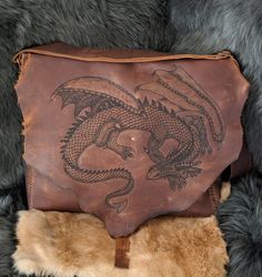 The Slumbering Dragon Messenger BagWe will make you a custom, unique bag just for you.Handmade, hand stitched, one of a kind leather messenger bag. It is made from extremely durable stone oil leather that offers beautiful color variation and texture as well as water resistance and lifelong use.The bag measures roughly 15 in by 13 in with a 3 in gusset. The front has three additional pockets one is 11.5 in by 8.5 in and the other two are 5 in by 6 in.The strap is completely adjustable and the str Hand-stitched Leather Shoulder Bag Gift, Artisan Leather Satchel As Gift, Artisan Leather Satchel Gift, Artisan Leather Satchel, Leather Bags For Everyday Use, Handmade Leather Artisan Satchel, Artisan Leather Saddle Bag Satchel, Artisan Leather Satchel Saddle Bag, Unique Leather Bag As A Gift