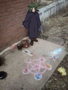 a person standing in front of a brick wall with chalk drawings on the ground next to it