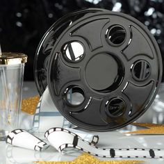 a black film reel next to a shot glass and gold confetti streamers