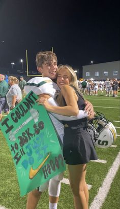 two people hugging each other on a football field