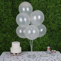 a cake and balloons on a table with confetti in front of green wall