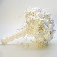 a bridal bouquet with white flowers and pearls on the stems is photographed against a white background