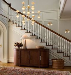 a living room area with a rug, cabinet and staircase leading up to the second floor