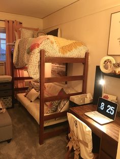 a bedroom with bunk beds and a desk in front of the bed has a laptop on it