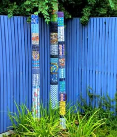 a tall blue pole sitting in the middle of a garden next to a blue fence