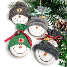 three snowman ornaments hanging from a christmas tree