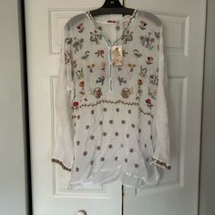 This Is A Gorgeous Johnny Was Cotton/Poly White Flowered Tunic Top Size Large Nwt. It Has Long Sleeves With Eyelid Lace, Half Button Down And Multicolored Either Flowers. Embroidered Long Sleeve Folk Tunic, Bohemian V-neck Tunic With Printed Motifs, Luxury Embroidered V-neck Tunic, Bohemian V-neck Tunic With Block Print, Johnny Was Clothing Shirts & Tops, Johnny Was, Tunic Top, White Flowers, Tunic Tops