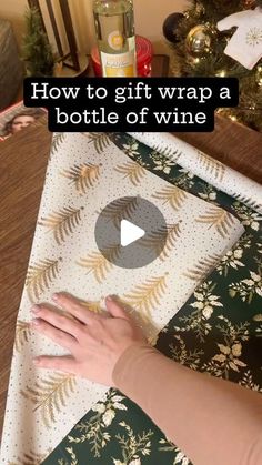 a woman is making a bottle of wine on a table with christmas decorations and presents