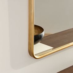 the reflection of a bowl in a mirror on a white wall with wood flooring