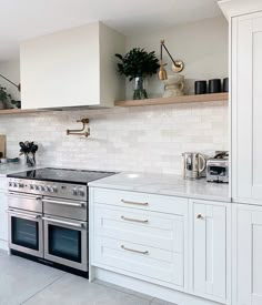 a kitchen with white cabinets and stainless steel stove top oven, built in shelving