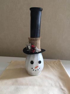 a white snowman with a black top hat and nose is sitting on a table