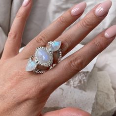 Aphrodite Sterling Silver Rainbow Moonstone Ring A ring fit for a queen and named after the Greek goddess Aphrodite who is associated with love, beauty, pleasure and passion. This deeply feminine and glowing ring has three mesmerising Ethically sourced Rainbow Moonstones and set on the most deliciously decorated band. Our jewels are here to make you feel empowered and radiant. * Mesmerising Statement Ring * Three large dreamy Moonstones * High quality Sterling Silver  * Ethically sourced Rainbow Moonstones * Lead & Nickel free * Each moonstone has its own natural sheen so your piece is practically a one of a kind! * Also available in 14K Gold Plating Rainbow Moonstone Wildly feminine and overflowing in goddess energy. Our dreamy Rainbow Moonstone promotes all kinds of magic and deliciousne Mystical Moon Phase Ring, Moon Phase Moonstone Rings, Moonstone Rings With Moon Phase Design, Spiritual Moonstone Crystal Ring, Healing Moonstone Ring With Natural Stones, Spiritual Stone Setting Crystal Ring, Spiritual Crystal Ring With Stone Setting, Spiritual Crystal Ring With Gemstone Accents, Mystical Crystal Promise Ring