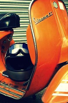 an orange scooter with a helmet and goggles on it's seat