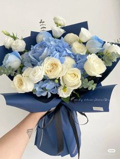 a bouquet of white and blue flowers is being held