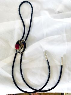 a black cord necklace with a red flower on it