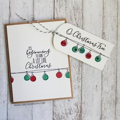 two christmas cards on a white wooden table with string lights and the words, beginning to look like christmas