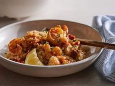 a white bowl filled with shrimp and rice next to a blue dish towel on top of a table