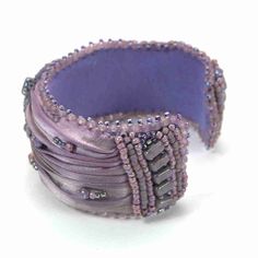 Beautiful one-of-a-kind muted pale lavender to pale pink ombre Shibori Silk ribbon open cuff bangle bracelet. A hand beaded crystal and purple beaded component adorns the center of this cuff bangle. With, light purple and pink Czech glass beads and tiny bronze & colored seed beads coyly peek out between the folds of the pure silk folds. The ends of the open cuff bangle bracelet are designed to finish the edges with interest, using small half tile beads in the continuing color theme. The reverse Handmade Adjustable Purple Cuff Bracelet, Adjustable Wearable Art Cuff Bracelet For Parties, Formal Adjustable Embellished Jewelry, Bohemian Beaded Bracelets For Formal Occasions, Elegant Beaded Cuff Bracelet As Gift, Elegant Beaded Cuff Jewelry, Elegant Beaded Cuff Bracelet For Gift, Beaded Cuff Bracelet Gift, Elegant Beaded Cuff Bracelets