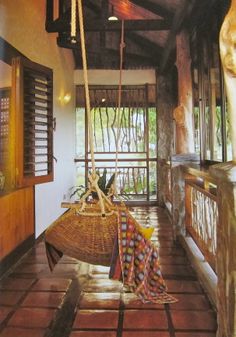 a hammock hanging from the ceiling in front of an open porch with wood shutters