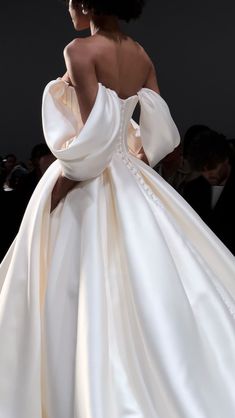 the back of a woman's wedding dress with an off - shoulder, flowing skirt