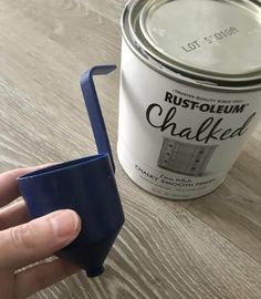 a hand holding a paint roller next to a can of rustoleum chalk