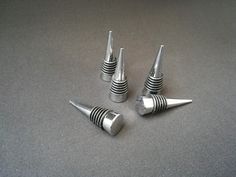 three metal screws sitting next to each other on a gray surface with black and white stripes