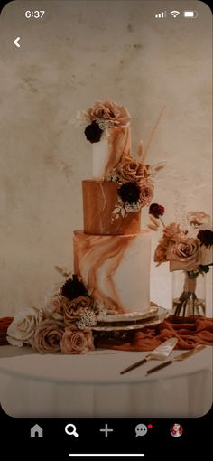 a three tiered cake sitting on top of a table next to two vases filled with flowers