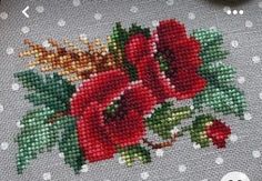 the cross stitch pattern has red flowers on it