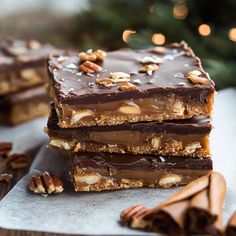 three pieces of pecan bar stacked on top of each other next to a christmas tree