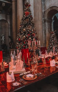 a dining table set up for christmas with a large tree in the center and decorations on it