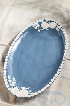 a blue and white plate sitting on top of a cloth covered tablecloth with an ornate design