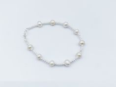 This enchanting bracelet is the epitome of versatile charm, making it the perfect choice for bridesmaids, everyday wear, and special occasions. Each lustrous freshwater pearl exudes natural beauty, handpicked for their radiant glow and refined grace. Interspersed among these pearls, the sterling silver beads add a touch of contemporary sophistication, creating a harmonious blend of classic and modern design. Elegance meets versatility as this bracelet effortlessly complements any attire. Whether Minimalist Hypoallergenic White Charm Bracelet, Pearl White Bracelet Jewelry As Bridesmaid Gift, Adjustable Pearl White Bracelet For Bridesmaids, Delicate White Bracelets For Bridesmaids, Adjustable Pearl White Jewelry For Bridesmaid Gift, Minimalist Sterling Silver Pearl Bracelet For Wedding, Delicate Adjustable Bracelet With Simple Design, Delicate White Bracelet For Bridesmaid, Delicate Adjustable Bracelets For Bridesmaid Gift