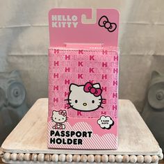 a hello kitty passport holder sitting on top of a wooden table next to a wall